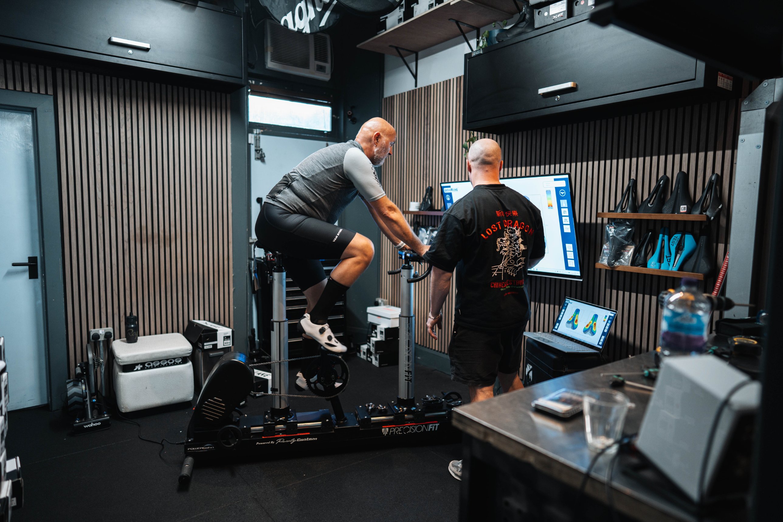 A rider on the Precision Fit adjustable fit bike in the Edinburgh Bike Fitting studio, with the fitter reading the pressure map on screen