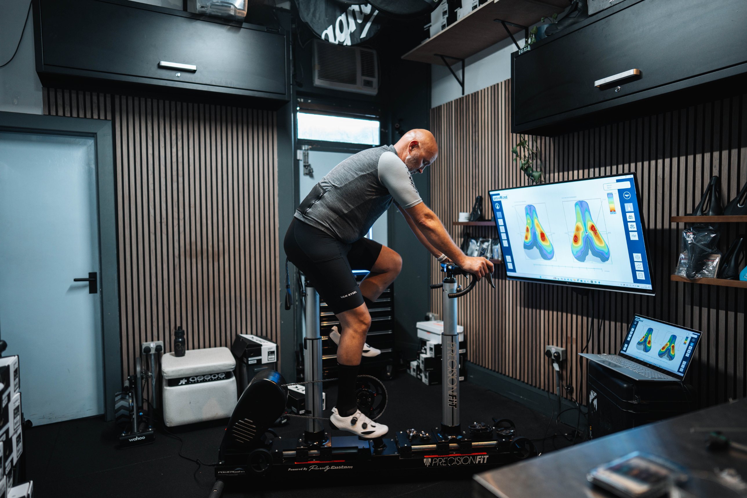 Rider on the fit bike while the saddle pressure map shows on the big screen